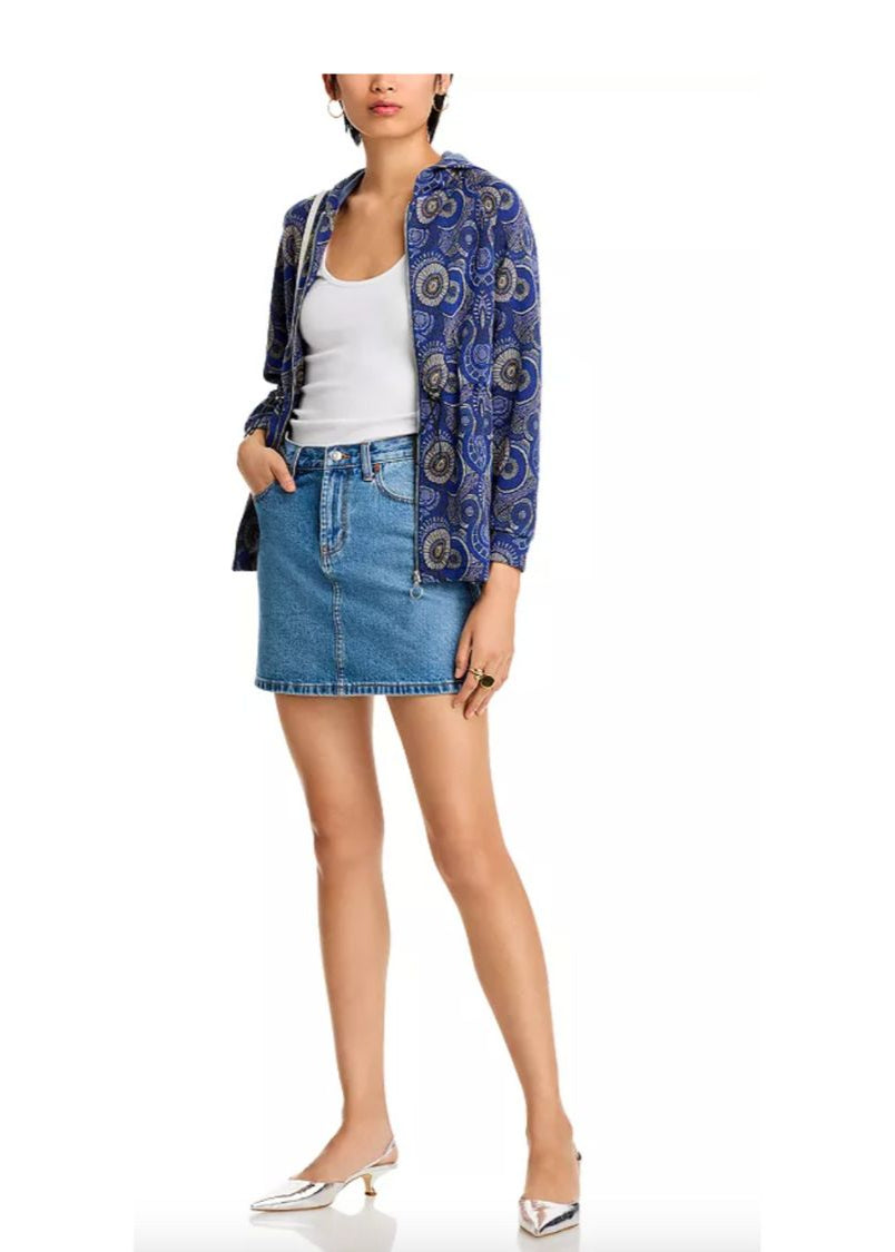 Woman wearing a blue patterned cardigan, white top, and denim skirt on a white background