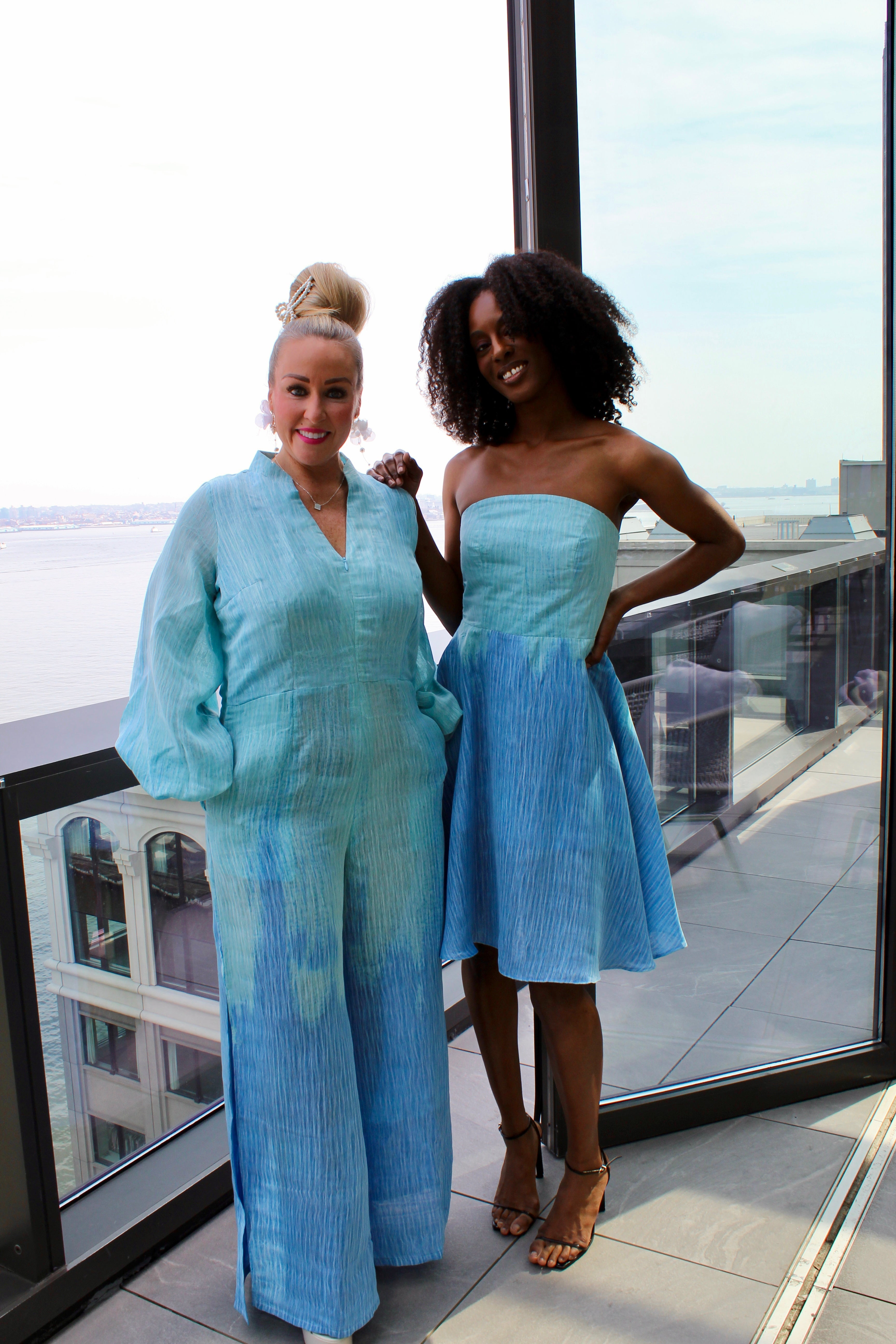 Full body image of white plus size woman wearing the Blue Ombre jumpsuit standing next to woman in the strapless dress as bridesmaids