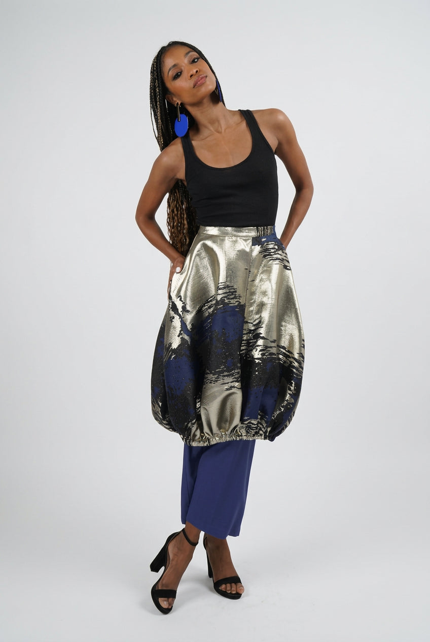 Woman wearing a black top and patterned skirt on a white background