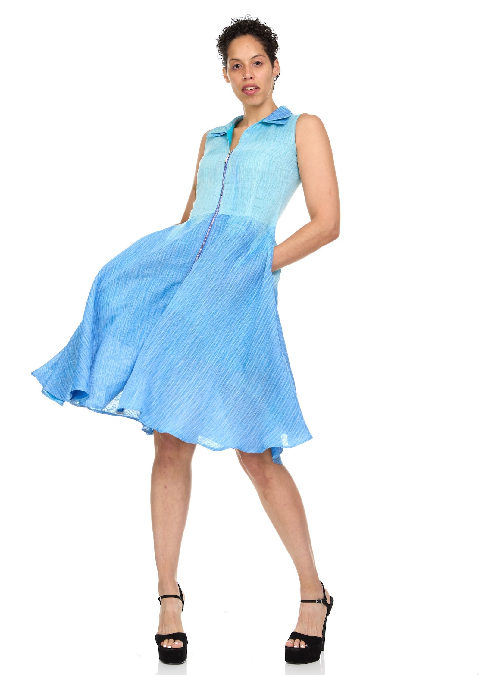 A model wearing a sleeveless, double-layered blue ombre organza dress with a double collar and side pockets.