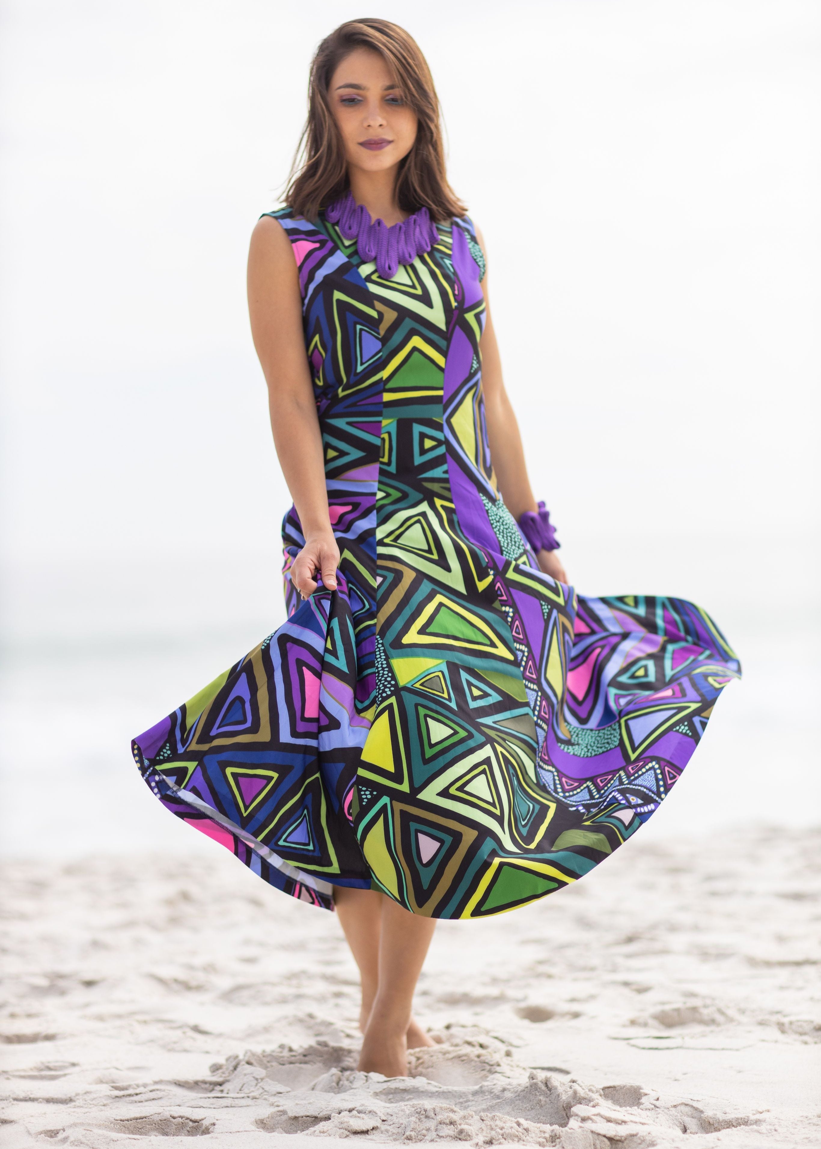 Woman wearing a colorful geometric-patterned dress on a beach. Perfect for destination wedding
