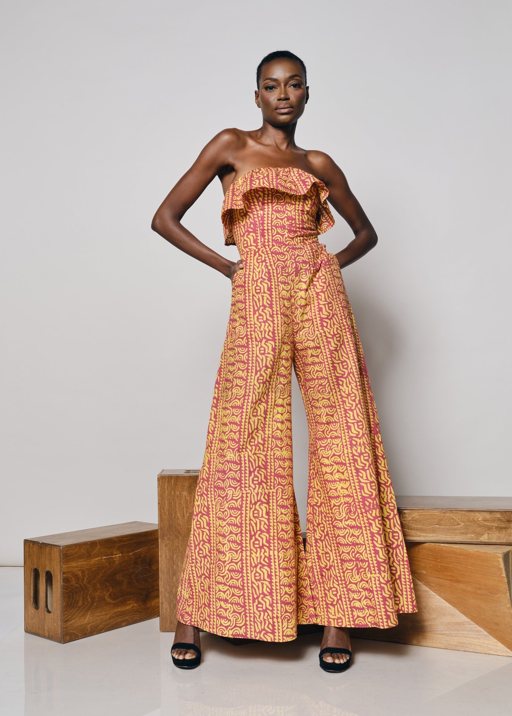 A model wearing the Senegal Jumpsuit in a vibrant pink and yellow print.
