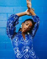 A woman posing against a blue backdrop in the Bahari Print Jumpsuit