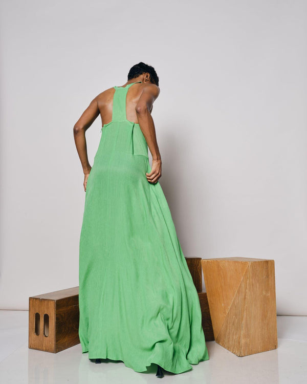 A side view of a woman wearing the Cape Verde Maxi Dress, standing by a wooden installation