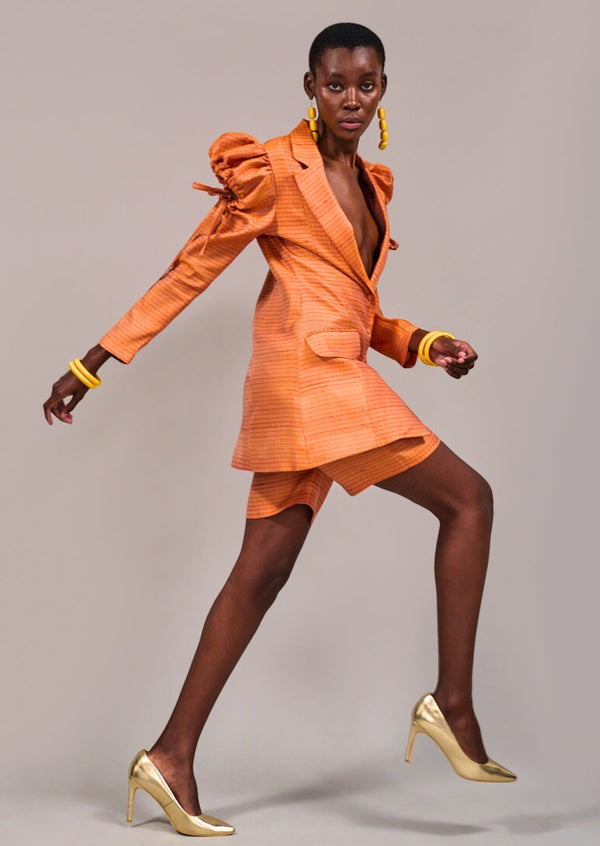 Model mid step wearing the Adderley Tuxedo Jacket and the Foreshore Bermuda Shorts by KAHINDO