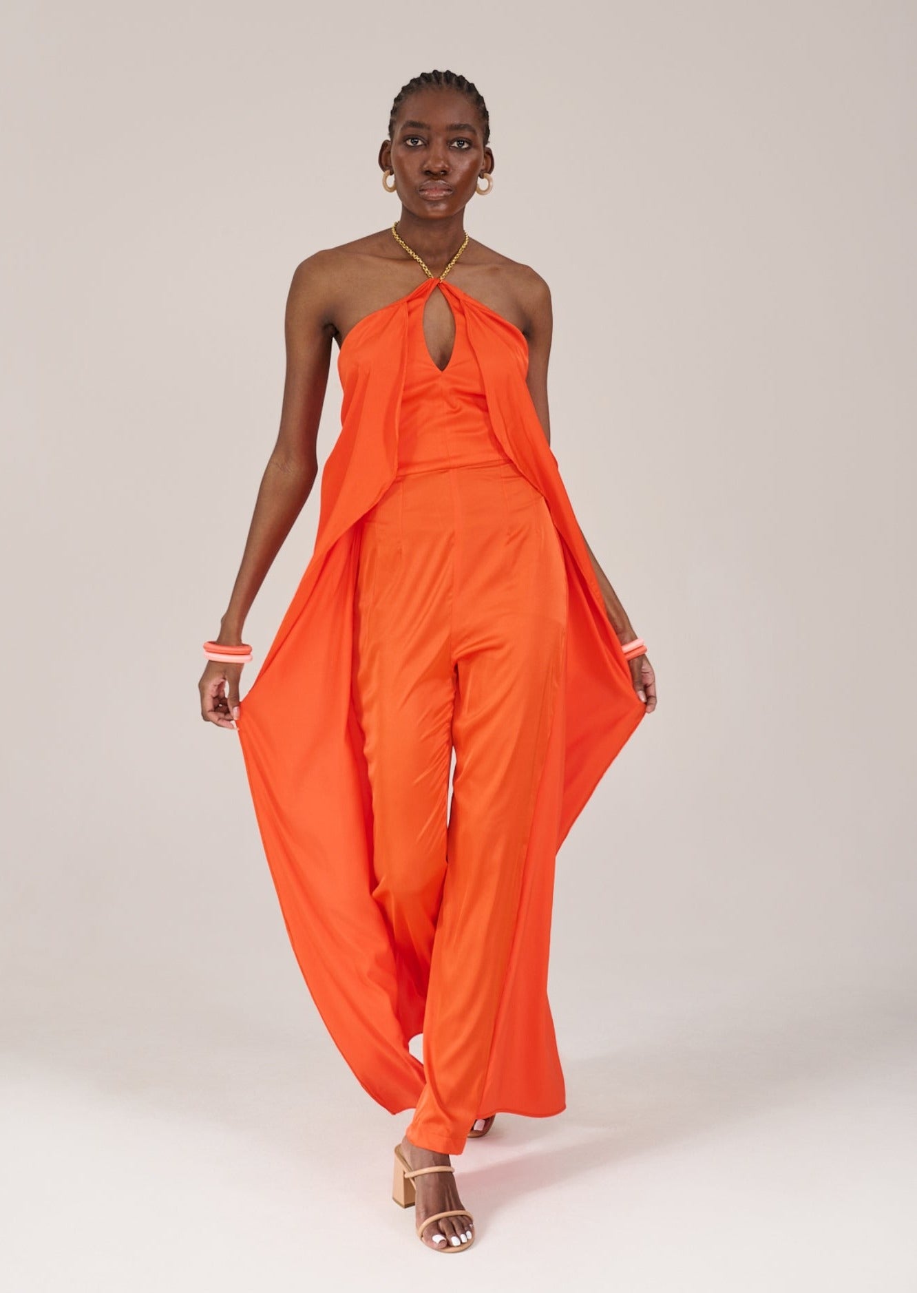 Model wearing the KAHINDO Imizamo Jumpsuit, walking forward lightly holding the fabric of the trousers