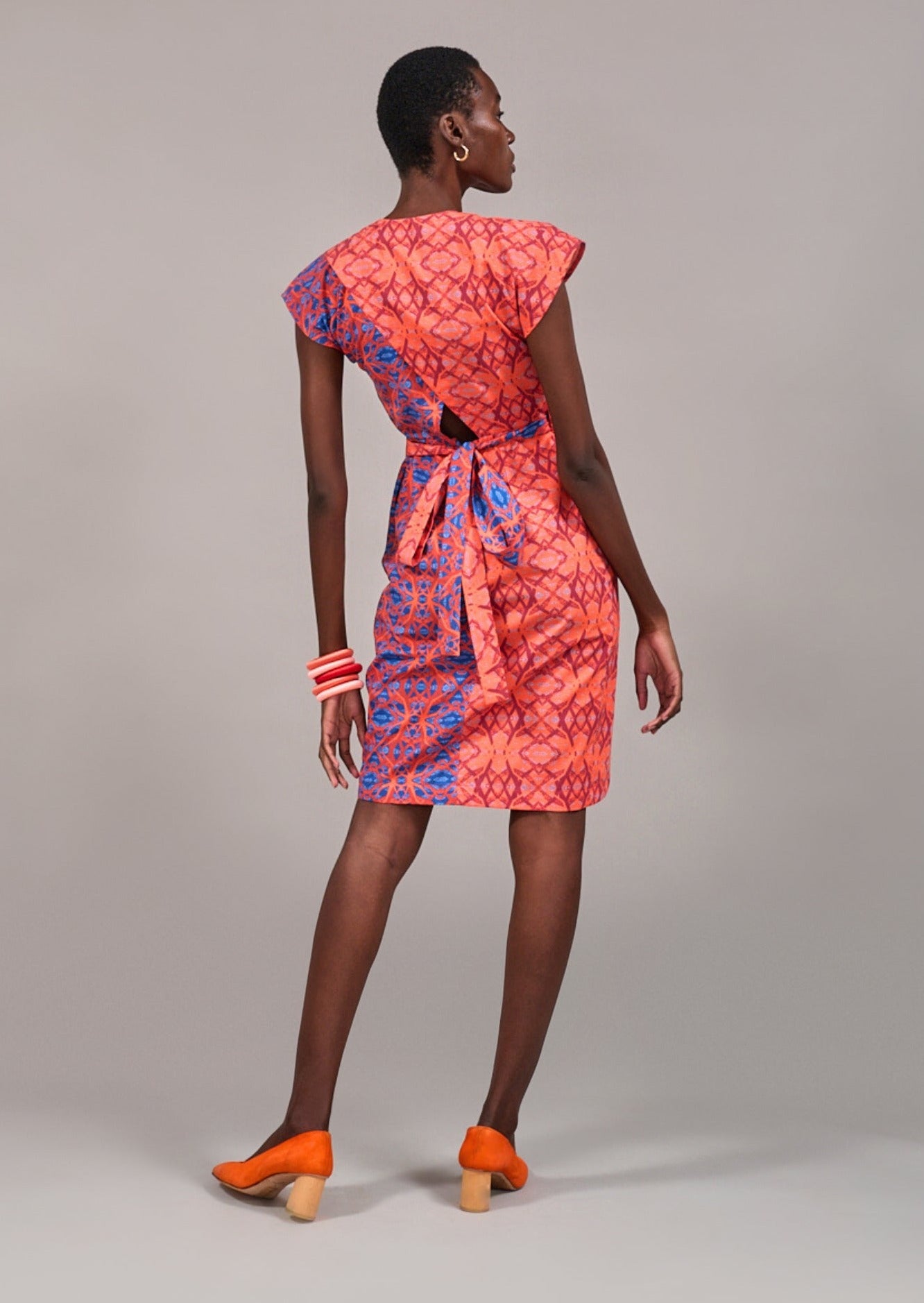 Model facing backwards wearing the KAHINDO Hermanus Wrap Dress showing the cut-out details and overlapping prints