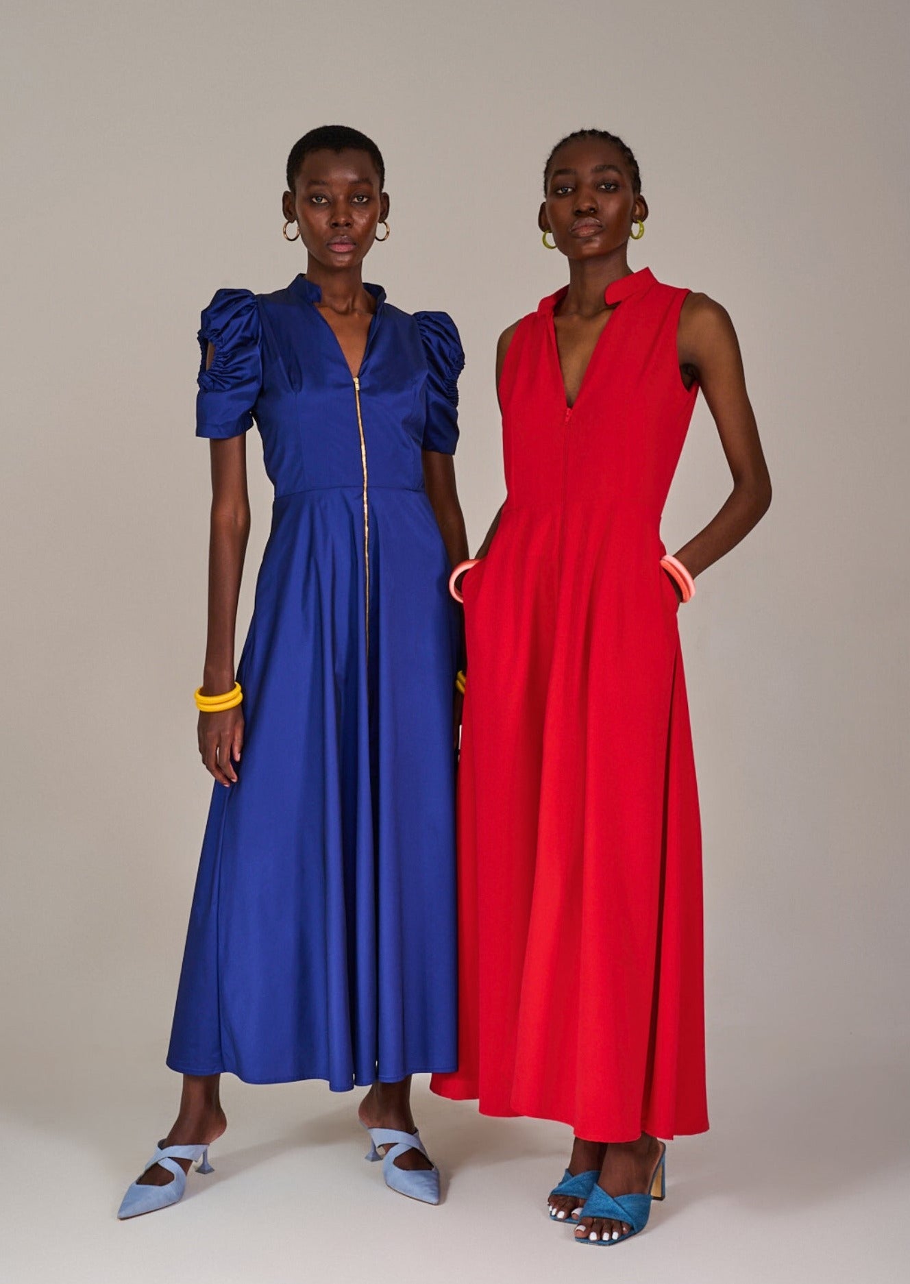 Model posing with hands in pocket wearing the Bokaap Orange Bamboo Dress, posing together with a model in the Nines Blue Dress by KAHINDO