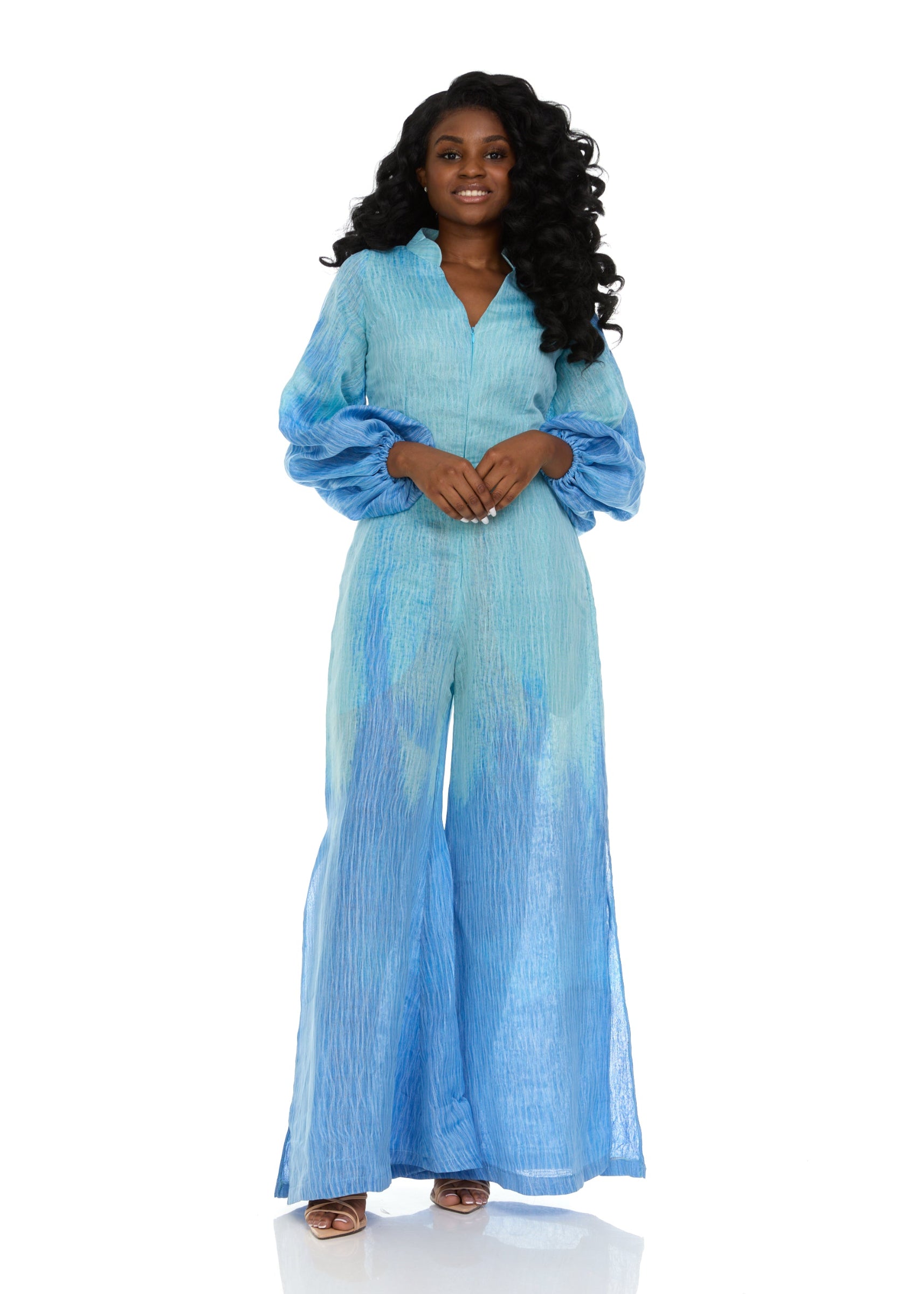 A woman modeling a blue organza jumpsuit with billowing balloon sleeves and a front zipper.