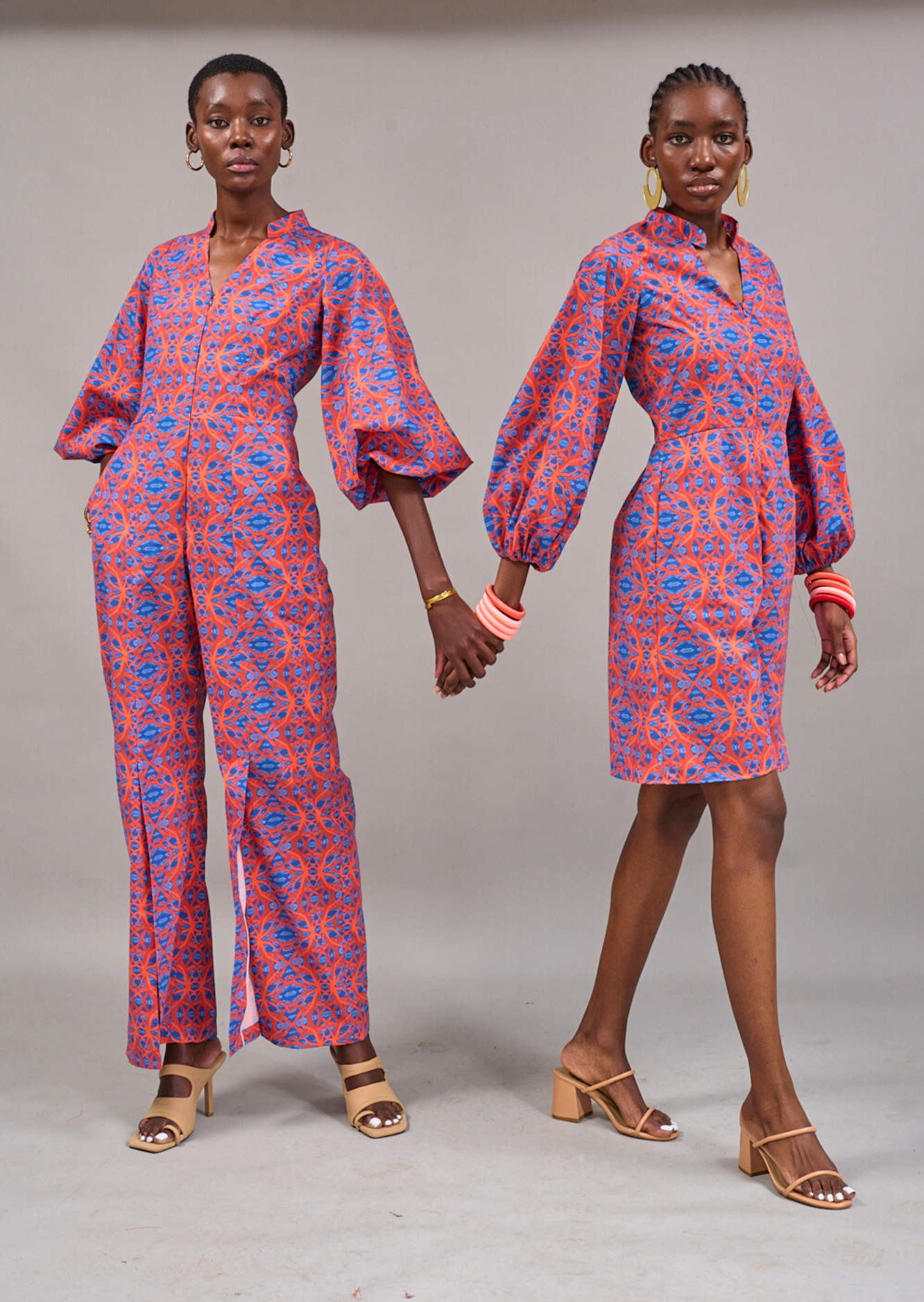 Two models posing together holding hands wearing the Nobu Jumpsuit and Claremont Romper by KAHINDO