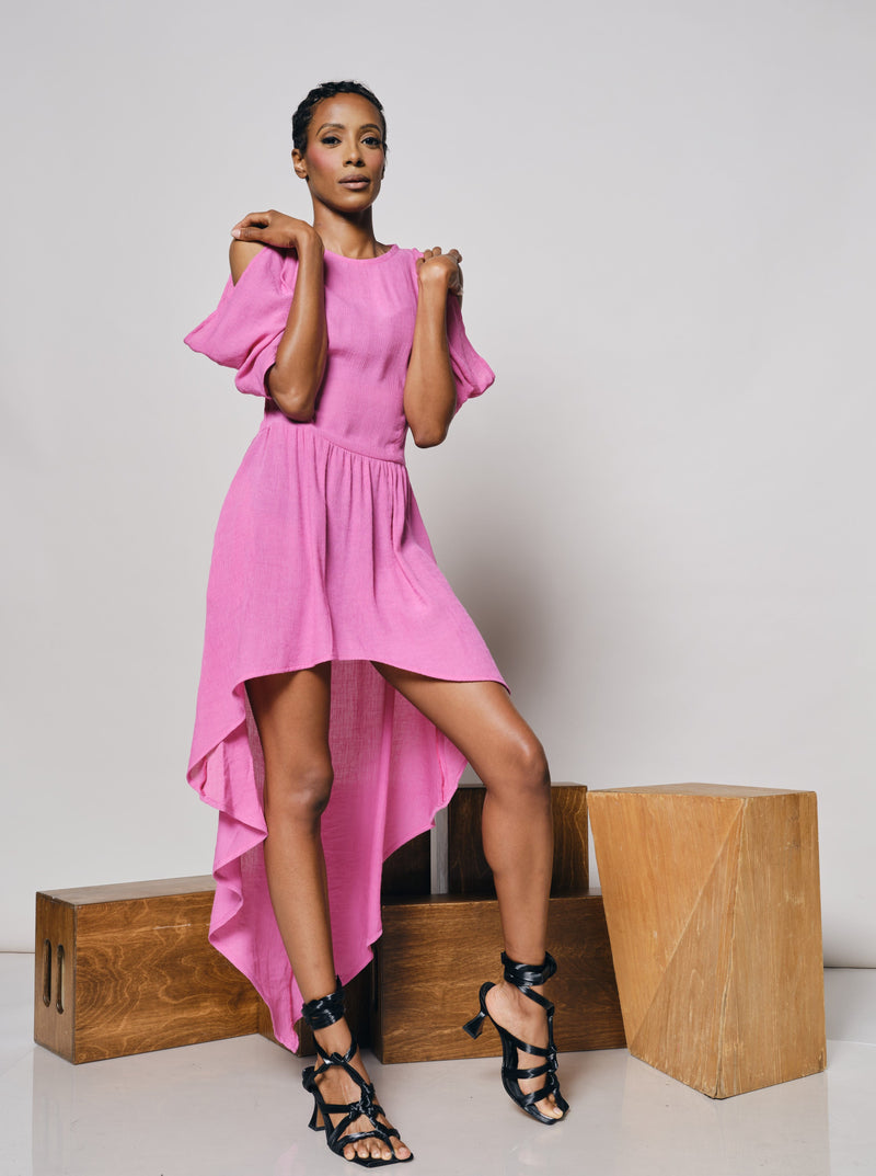 Model in a high low pink spring dress holding cut out at shoulders