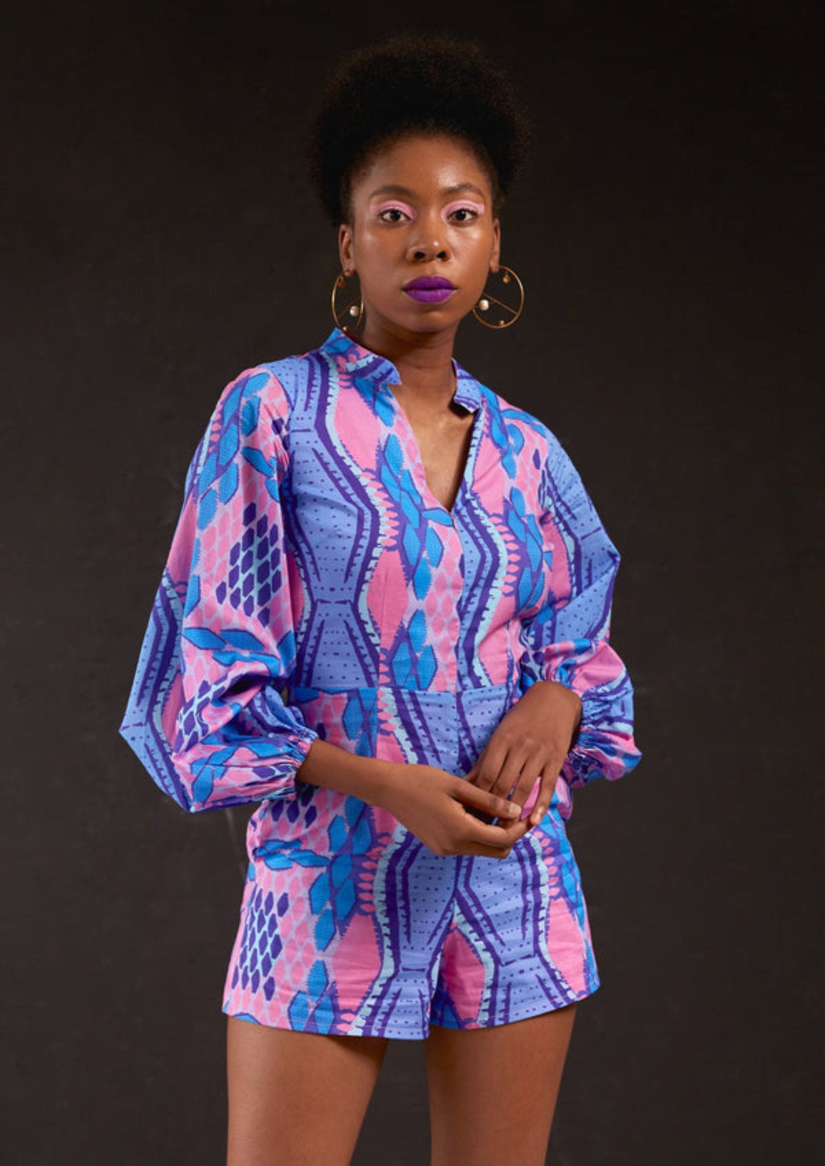 Woman wearing a blue and pink patterned outfit against a black background