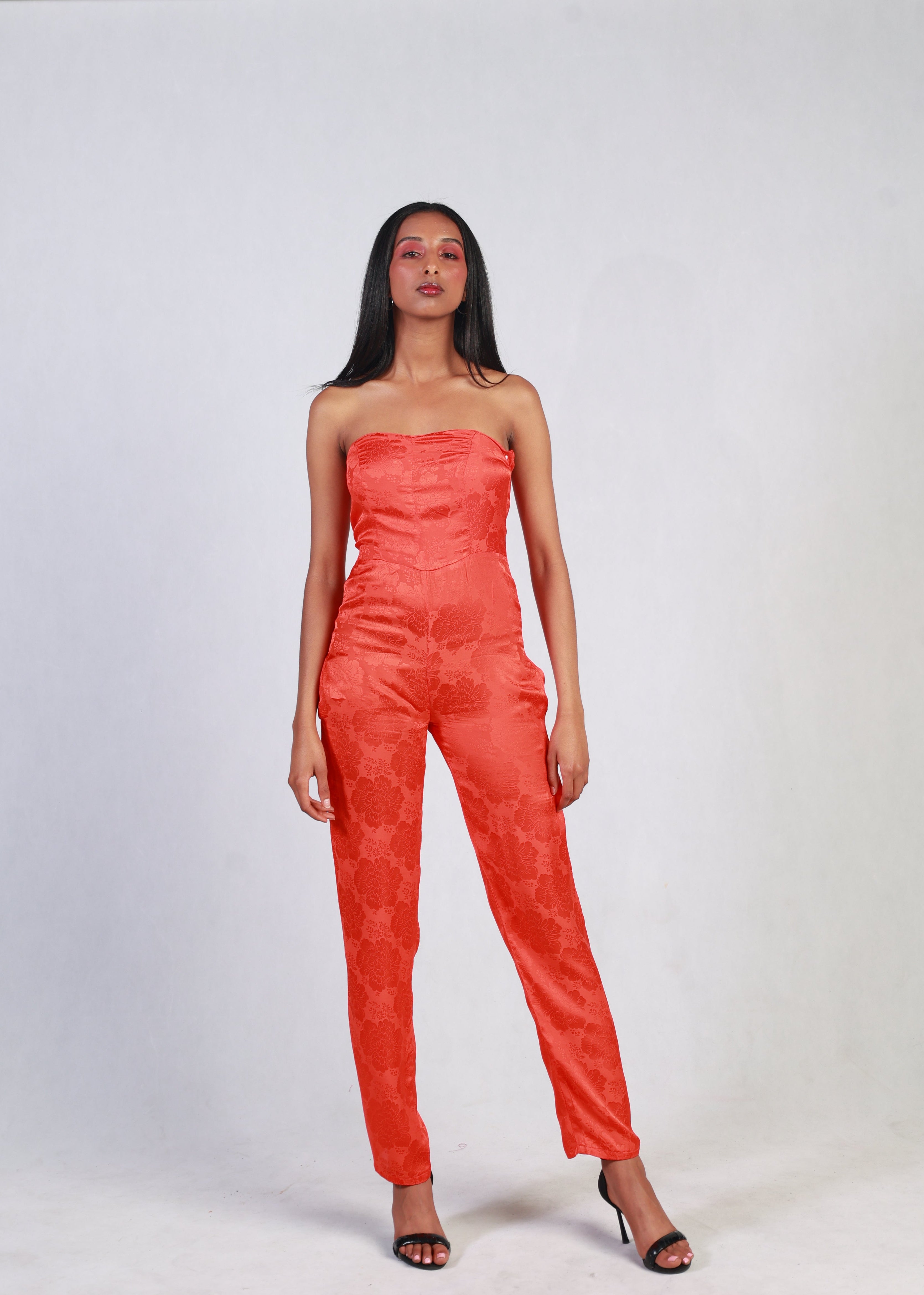 Woman wearing a red strapless jumpsuit on a white background