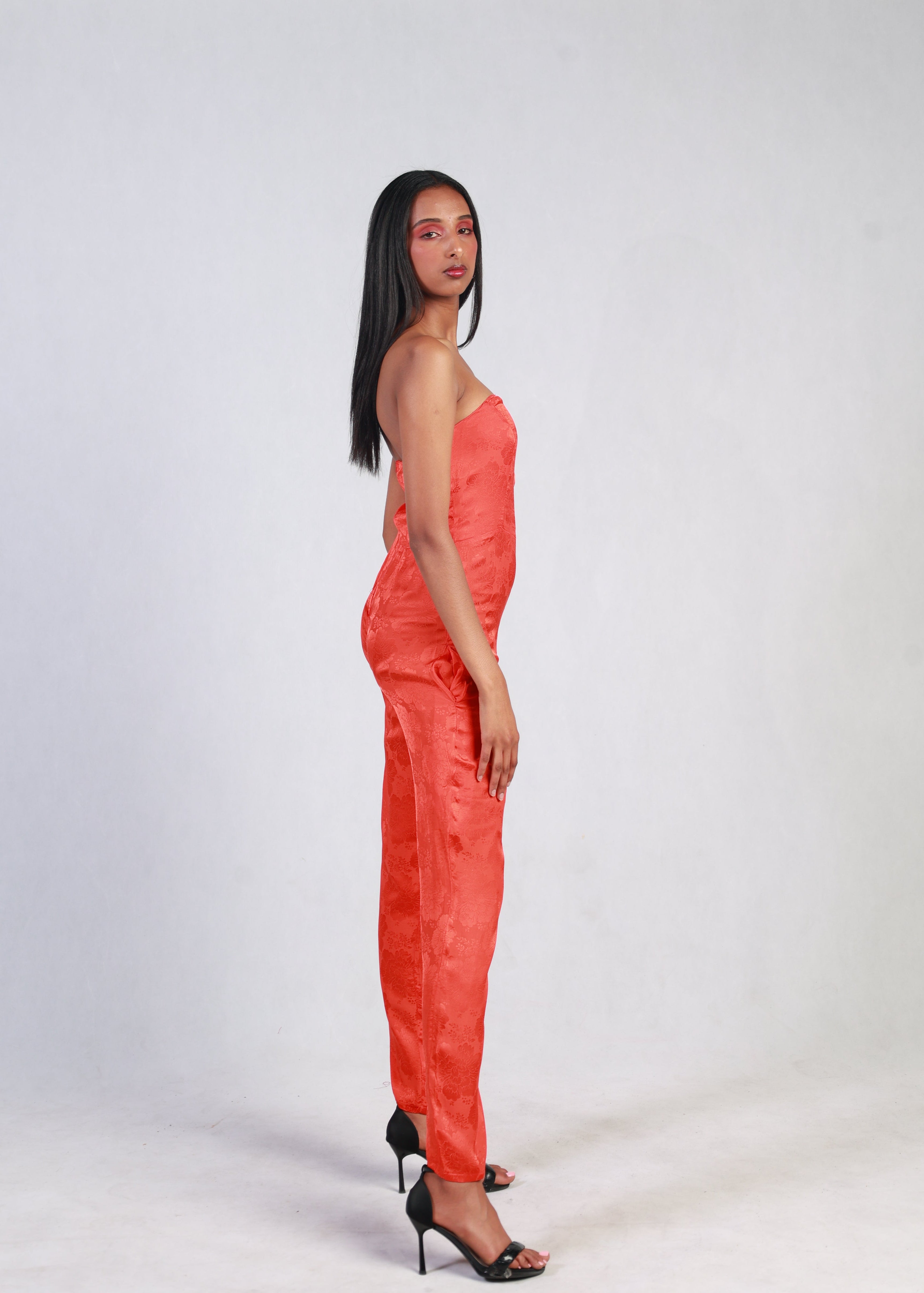 Woman wearing a bright red jumpsuit against a white background