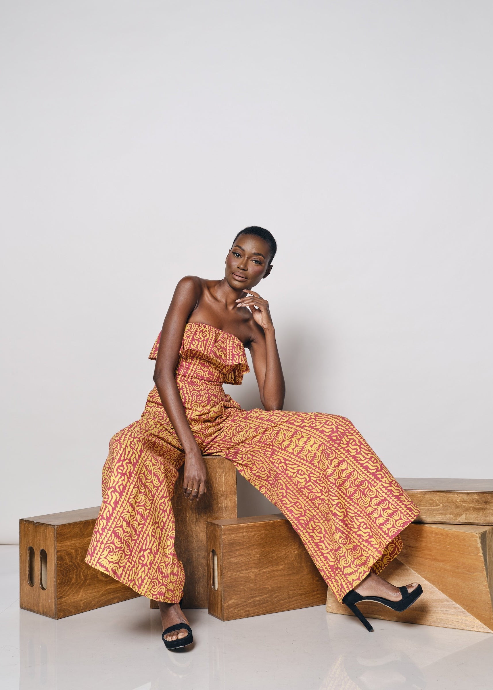 A model wearing the Senegal Jumpsuit in a vibrant pink and yellow print.