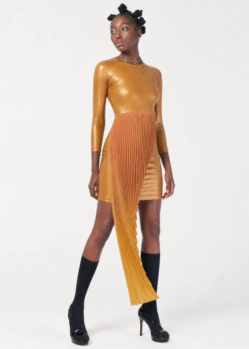 Sibayi Midi Dress in a metallic gold stretch fabric featuring a fitted long-sleeve silhouette with a unique asymmetrical pleated panel cascading from the waist. Styled with black knee-high socks, black platform shoes, and layered gold necklaces against a clean white studio background, showcasing the dress's sculptural, contemporary design.