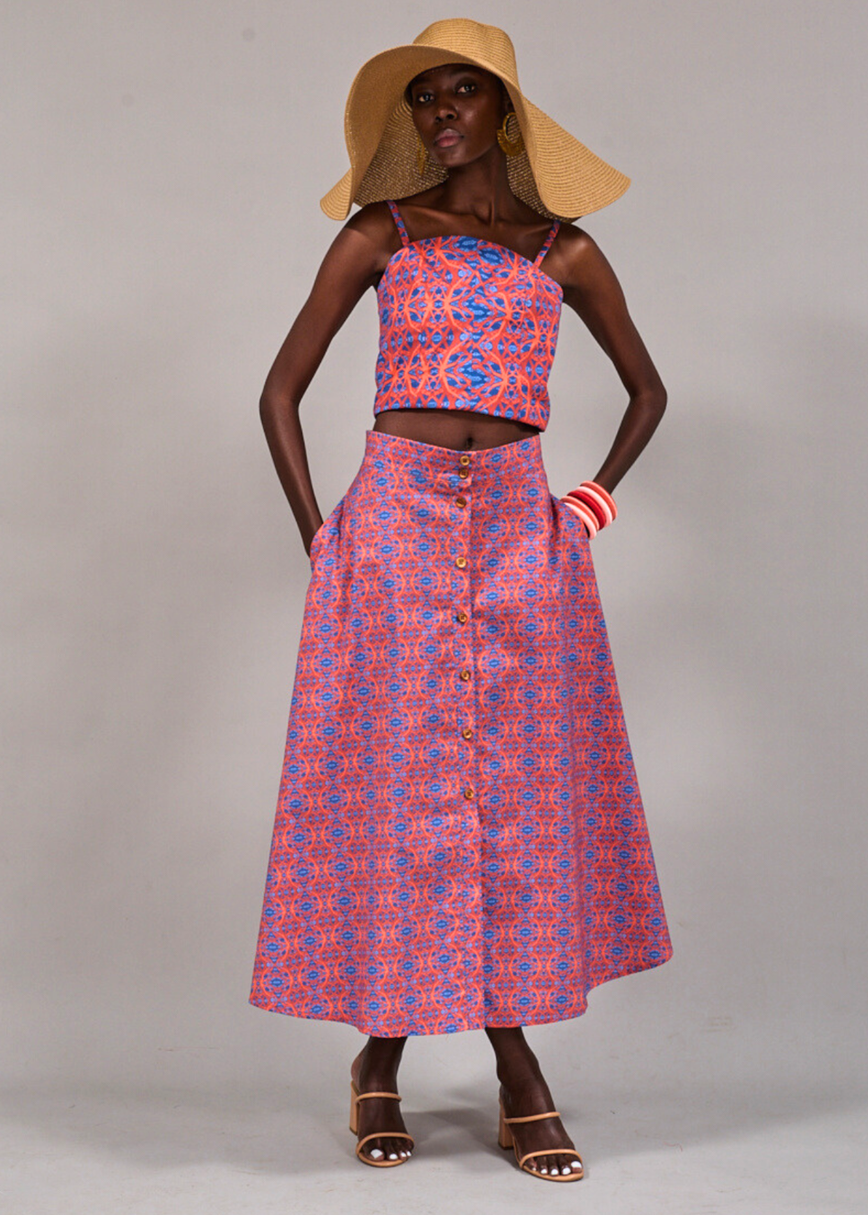 Model posing with hands in pocket and wearing a wide brim straw hat in the Tang Top and Camps Bay Skirt