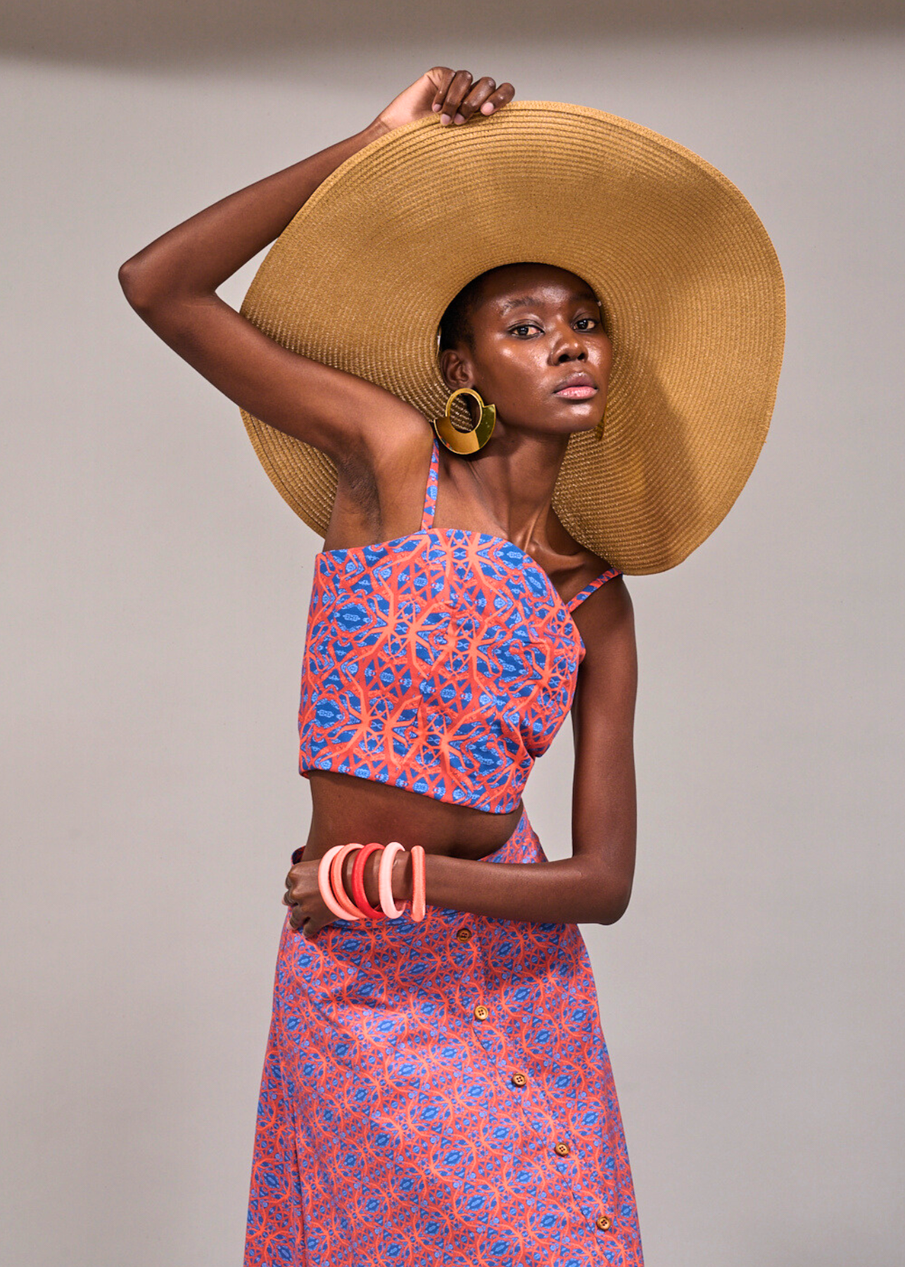 Model posing with one hand on her wide brim straw hat and another around her waist wearing the KAHINDO Tang Top and Camps Bay Skirt