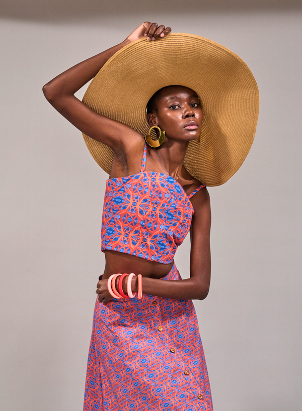 Model posing with one hand on her wide brim straw hat and another around her waist wearing the KAHINDO Tang Top and Camps Bay Skirt