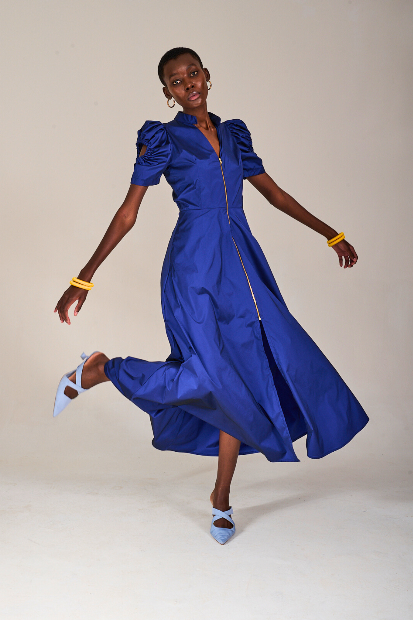 Model standing on one foot wearing The KAHINDO Nines Blue Dress, styled with pale blue heels