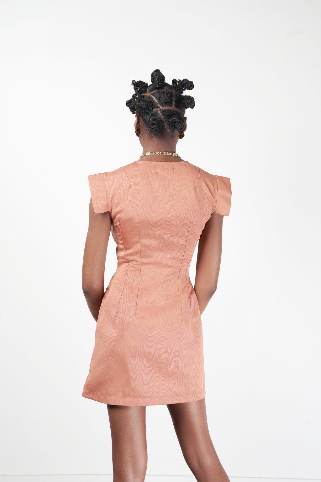 The Congo Top worn by a woman with black hair, styled with a peach skirt