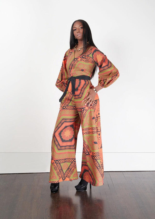 Side angle of a woman dressed in the Sondu Jumpsuit with orange and black print detailing