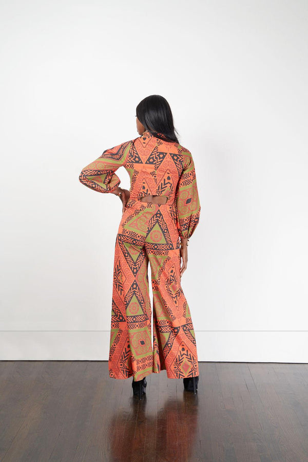 Rear perspective of a woman modeling the Sondu Jumpsuit with an orange and green design