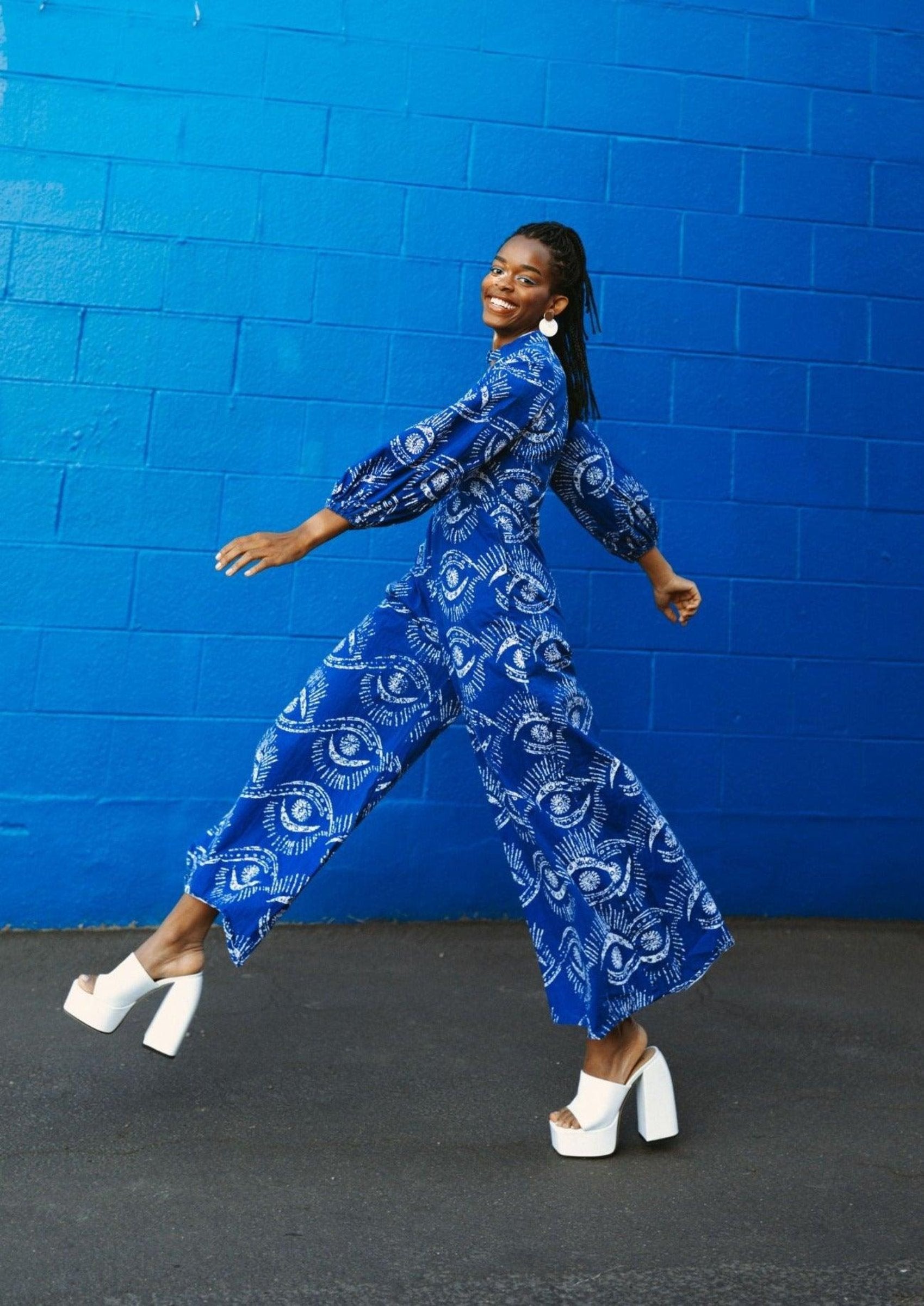 A female model showcasing the Bahari Print Jumpsuit paired with white shoes