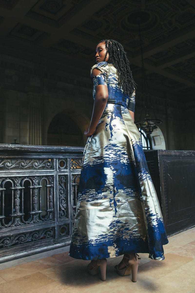 Full-length view of the Cleopatra Maxi Dress worn by a model in an elegant hallway
