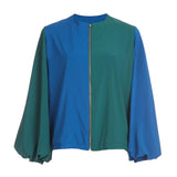 A color block bomber jacket featuring green and blue sections with zipper details