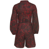 Close-up of the Kalenjin Romper's red and black leaf pattern fabric
