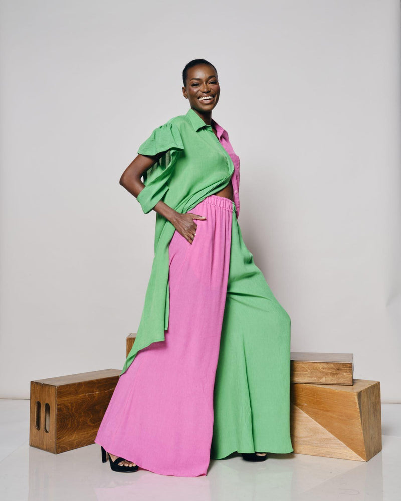A woman modeling the Zanzibar Shirtdress with a green and pink pattern